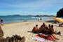 galera tocando um viol&atilde;o na praia do canto do morcego e outra nadando em suas &aacute;guas l&iacute;mpidas