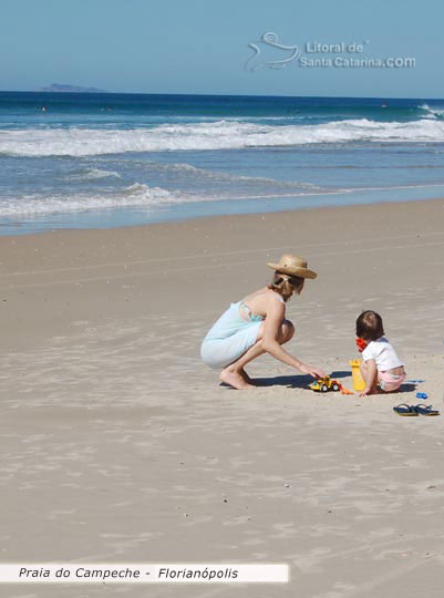 M�e brincando com a filha na areia da praia do campeche florian�polis