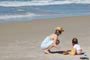 M�e brincando com a filha na areia da praia do campeche florian�polis