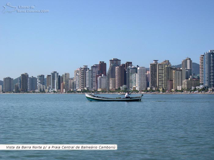 Vista da praia central de Balneário Camboriú, pescador em busca da tainha e ao fundo prédios grandiosos na orla da praia.