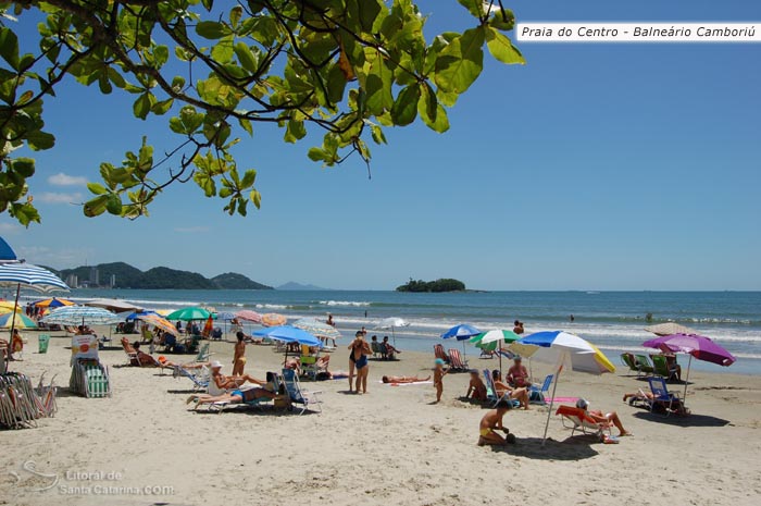 Crianças se divertindo na praia central de Balneário Camboriú e famílias tomando um sol na areira da praia.