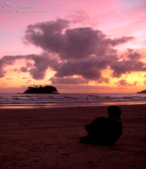 Criança adimirando o nascer do sol na praia central de Balneário Camboriú.