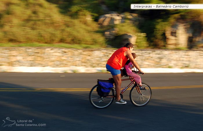 Pai e filha passeando de bicicleta pela rodovida interpraias em Balneário Camboriú.