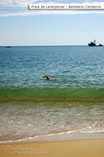 Senhor nadando sozinho nas águas cristalinas da praia de laranjeiras em Balneário Camboriú - Santa Catarina.