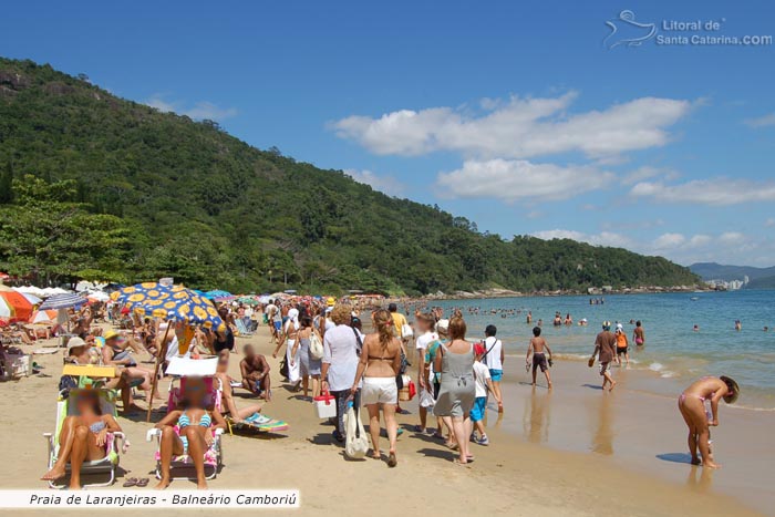 Famílias aproveitando o sol forte da praia de laranjeiras em Santa Catarina no verão.
