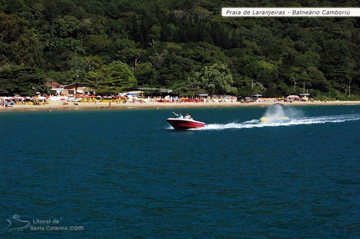 Barco chegando na praia de laranjeiras em balneário camboriú e ao fundo uma mata linda ainda preservada.