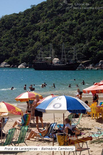 Algumas pessoas tomando sol e outras se divertindo nas águas límpidas da praia de laranjeiras em balneário camboriú.