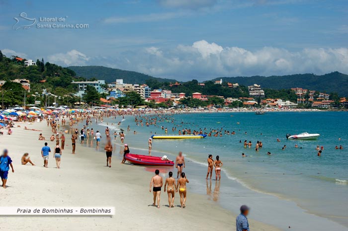 Praia de Bombinhas, pessoas fazendo caminhada na praia em uma linda tarde de sol.