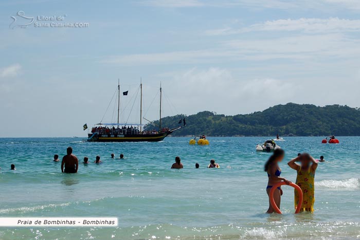 Famílias se divertindo na Praia de Bombinhas e ao fundo o fantástico barco pirata.
