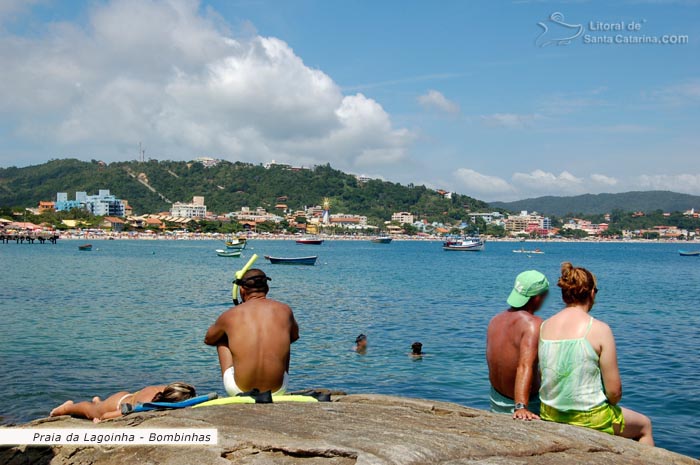 Pessoas relaxando em cima da pedra na Praia da Lagoinha em Bombinhas.
