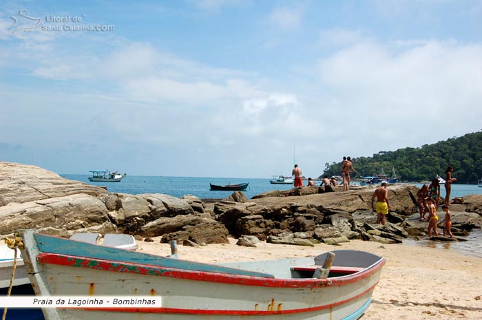 Barco de pesca e pessoas ao fundo se divertindo na Praia da Lagoinha em Bombinhas