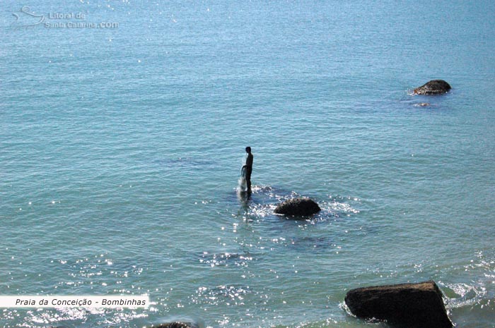 Pescador solitário em cima da pedra em busca da tainha na Praia da Conceição em Bombinhas.