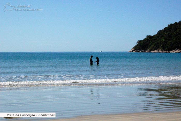 Casal namorando dentro das águas calmas da Praia da Conceição em Bombinhas.