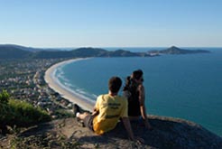 Casal em cima do morro deslumbrado com a vista do  Parque Municipal do Morro do Macaco em Bombinhas - Santa Catarina