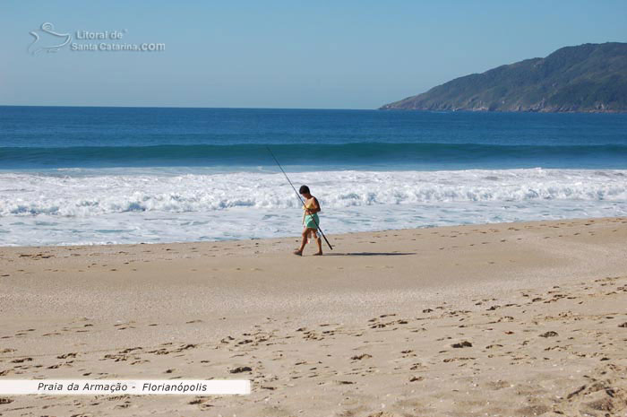 garoto indo fazer uma pesca na praia da armação em florianopolis