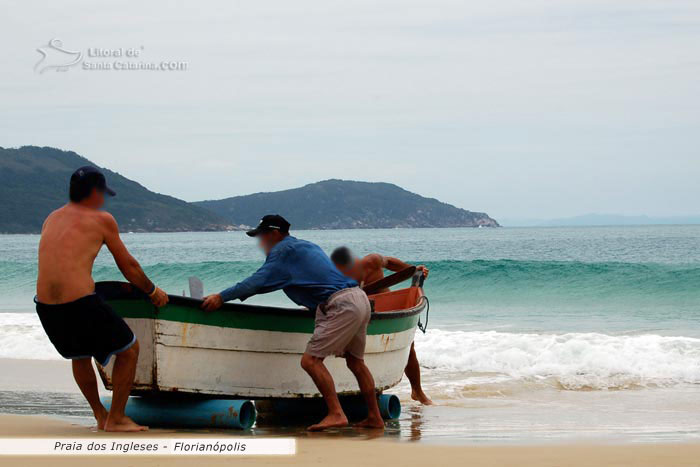 Pescadores puxando o barco do mar dos ingleses