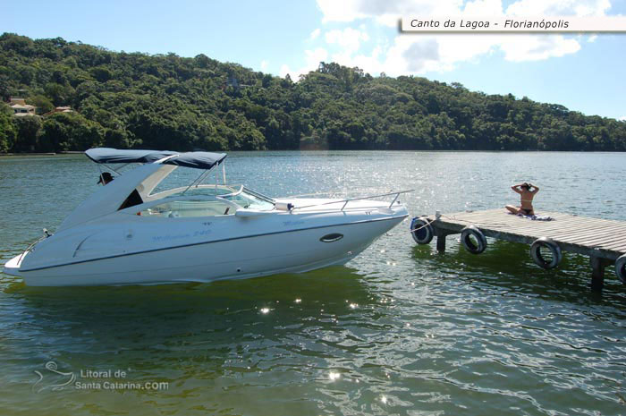 Lancha na lagoa da conceição, gata tomando um sol e ao fundo um cenário lindo do litoral sc