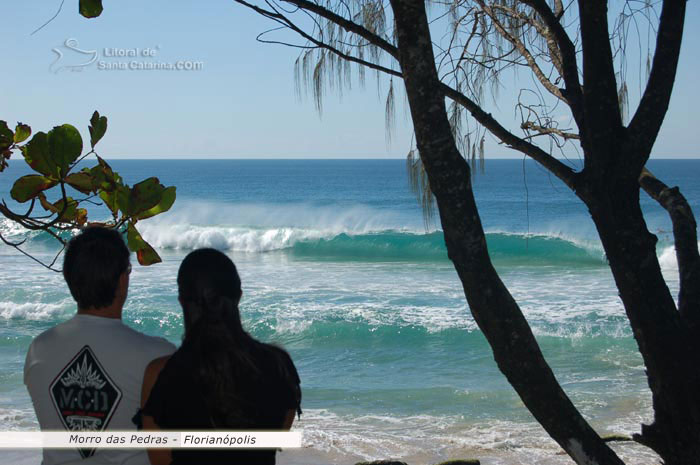 casal adimirando as altas ondas do morro das pedras em florianpolis