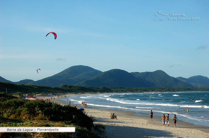 Barra da lagoa em floripa, pessoas fazendo um kite surf, outras caminhando calmamente nesta beleza de praia catarinense