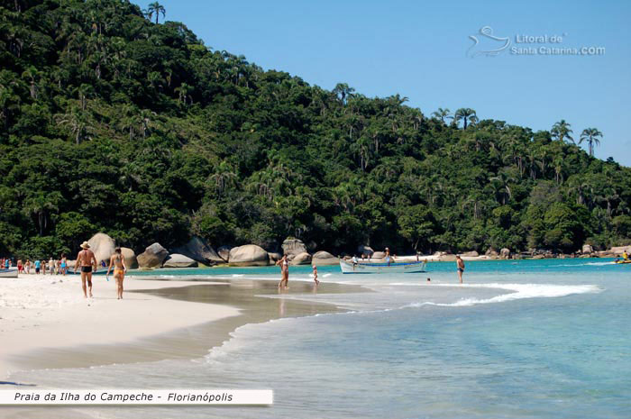 Floripa, Ilhado Campeche, pessoas passeando pela areia e outra adimirando as belezas naturais desta ilha