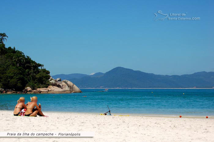 Garotas sentadas nas areias da ilha do campeche, observando o paraíso de sta catarina