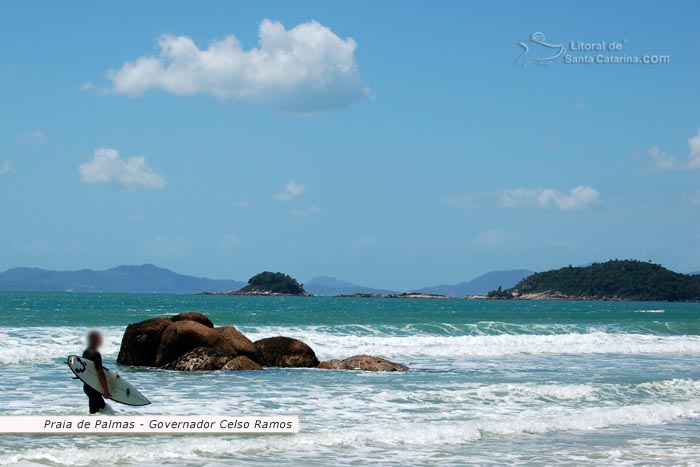 Surfista caminhando com sua prancha a beira mar, procurando um pico irado na praia de palmas em santa catarina.