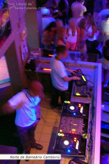DJ tocando na Balada de Camboriú e  ao fundo a galera dançando muito.