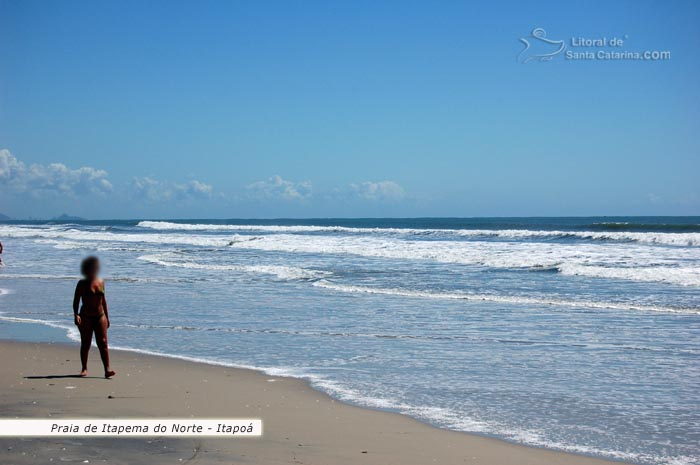 senhora andando tranquilamente a beira mar da praia de itapema do norte em itapoá sc