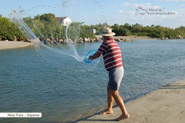 Senhor jogando tarrafa para pescar um peixe no canal da meia praia em itapema.