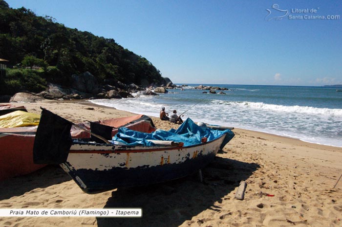 Barco de pesca e ao fundo dois pescadores em busca de um peixe.