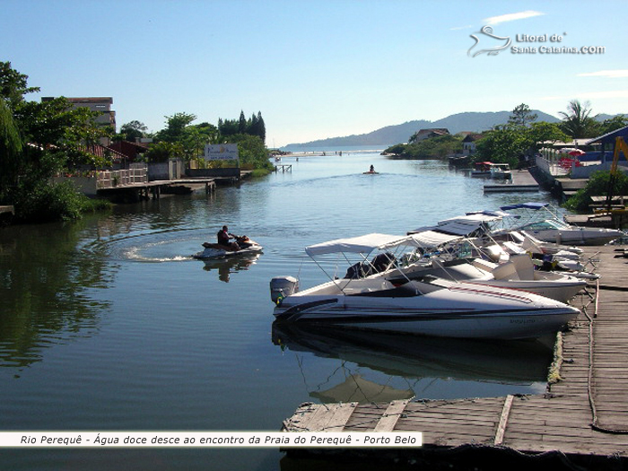 Rio Perequê, lanchas paradas na marina, outras pessoas saindo de jet ski e ao fundo a praia do perequê em porto belo.