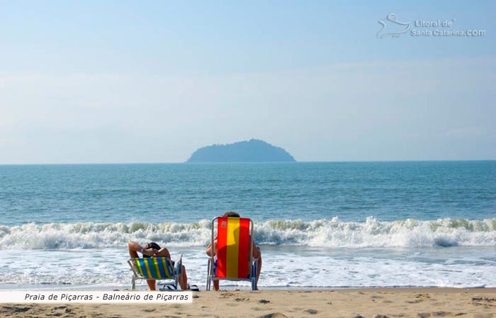 praia de piçarras, sc, brasil, e ao fundo a ilha feia, casal tomando um sol