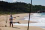 Pescador colocando a isca no anzol para  pescar na praia de taquarinhas em Balneário Camboriú.
