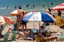 Algumas pessoas tomando sol e outras se divertindo nas águas límpidas da praia de laranjeiras em balneário camboriú.