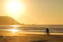 Nascer do sol na Praia de Mariscal  em Bombinhas e um senhor passeando calmamente de bicicleta pela praia, contemplando a natureza.