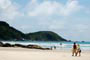 Praia de Mariscal, garoto e menina caminhando em busca da onda perfeita.