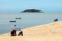 Pessoa tomando sol nas dunas dos ingleses e ao fundo um mar paradisíaco de santa catarina