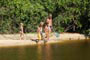 pai e filhos brincando de pegar peixinhos no riozinho da praia da lagoinha