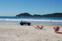 Bugui na praia do campeche em floripa, pessoas dencansando a beira mar e ao fundo o mar azul e ilha do campeche