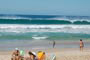 Surf Campeche, altas ondas rolando no pico e algumas pessoas relaxando nas areia da praia do campeche, santa catarina