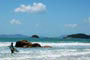 Surfista caminhando com sua prancha a beira mar, procurando um pico irado na praia de palmas em santa catarina.