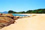 Praia grossa em Itapema, areias brancas, mar azul e ao fundo a mata atlântica ainda preservada.