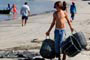 Garoto levando o cesto para encher de peixes no canto da praia em itapema.