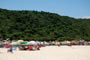 pessoas tomando sol e outras em baixo do guarda sol na praia da guarda