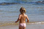 criança indo brincar nas águas límpidas da praia do araçá de porto belo sc